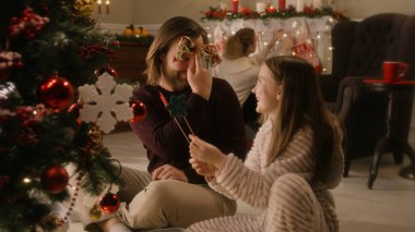 Babam kızıyla oturma odasında yerde oturur ve ağaç topları ve oyuncaklarla oynar. Hafif pijamalı genç kız Noel ağacını süslüyor. Noel 'den ya da Yeni Yıl' dan önce aile evi hazırlığı.