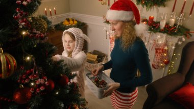Anne ile kızı topları ve oyuncakları seçiyor, Noel ağacını süslüyor. Pijamalı genç kız şeker yalıyor ve Noel tatilinden önce evi hazırlamak için anneye yardım ediyor. Sıcak bir evde kışın büyüsü.
