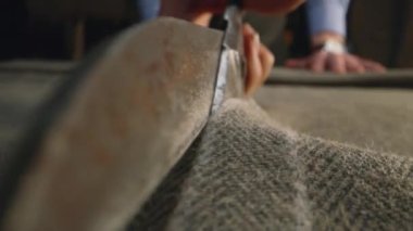 Close-up shot of tailor cutting textile according to sketch using scissors for sewing. Process of making clothes in luxury designer atelier or tailoring studio. Fashion and hand craft concept.