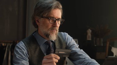 Tailor using tablet, transferring money on bank card, paying for service online during work in luxury atelier. Female tailor works on elegant suit on background. Fashion and entrepreneurship concept.