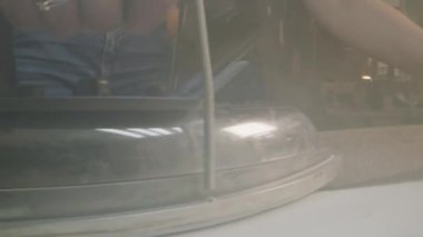 Close-up shot of woman irons fabric textile for future clothes. Seamstress works at sewing machine on background. Atelier sewing workshop. Concept of fashion, tailoring industry and hand craft.