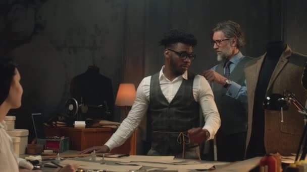Male Tailor Measures African American Man Discusses Female Tailor Design — Vídeo de Stock