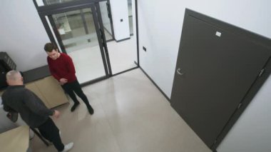 İki adam salonda kahve makinesinin yanında durur, sohbet eder ve molada işi tartışırlar. İş merkezindeki ya da ofisteki güvenlik kameralarından görüntüler. CCTV, izleme ve güvenlik kavramı. Güvenlik kamerası kaydı..