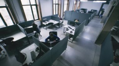 Ofiste modern tasarımla çalışan ve bilgisayarlı masaların başında oturan insanlar. Adam koridorda yürüyor, iş arkadaşına geliyor ve proje görevine yardım ediyor. İş birliği kavramı. Güvenlik kamerası..