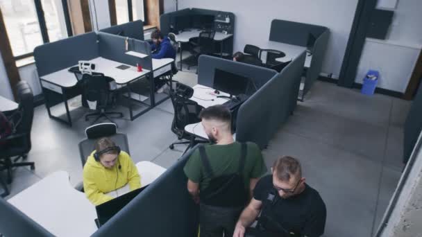 在办公室工作 坐在电脑桌旁的人 机修工让女人站起来 和同事一起在笔记本电脑上通过摄像头观看照片 并设置视图 安保摄像头拍摄 — 图库视频影像