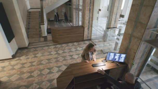 从酒店或商务中心办公室入口的监控摄像头观看 男警卫坐在接待处 在计算机上观看摄像机的回放 监测和安全的概念 — 图库视频影像