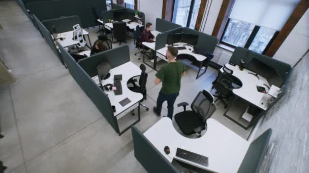 オフィスで働いてる 同僚はコンピュータとテーブルのそばに座っている 男は職場から立ち上がる 廊下を歩いている同僚 女性は電話でチャットする 同僚のItオフィスで働いています 防犯カメラ — ストック動画