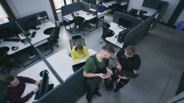 在办公室工作的成功人士 具有现代设计 并与计算机坐在桌旁 协同机械师在笔记本电脑上观看图片 转动并安装监控摄像头 安全摄像头拍摄 — 图库视频影像