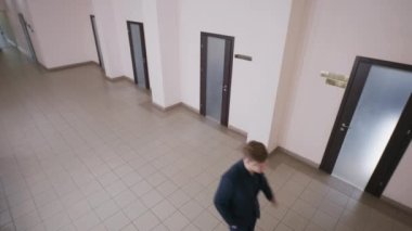 Ofis koridorundaki iş adamları. Zarif takım elbiseli başarılı bir adam koridorda yürüyor ve müşteriyle telefonda sohbet ediyor. Çalışma kağıtları olan kadın sekreter kabineden çıkıyor. CCTV kavramı. Güvenlik kamerası.