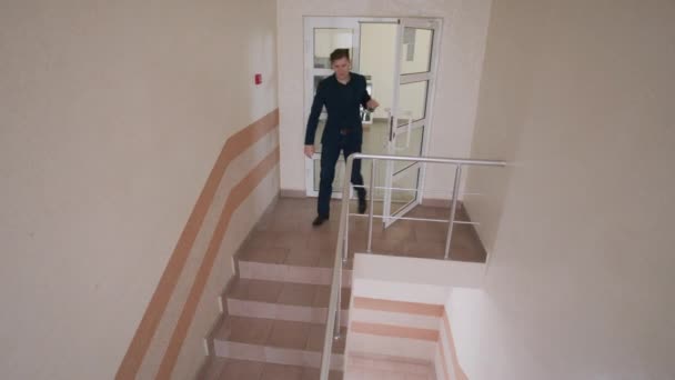 エレガントなスーツの成功した男はドアを開き 下の階の階段で降りてきます 仕事のプロセスの間の現代的なビジネスセンターオフィスの階段のビジネスの人々 防犯カメラとCctv — ストック動画