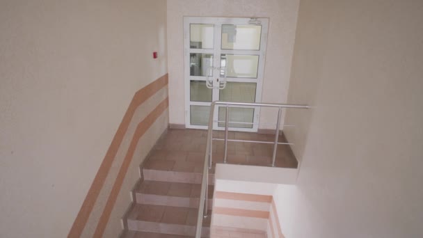 大人の男が上の階の階段を上ってドアを開ける 同僚が廊下を歩く 仕事のプロセスの間の現代的なビジネスセンターオフィスの階段のビジネスの人々 防犯カメラとCctv — ストック動画