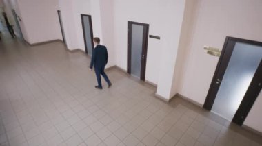 Ofis koridorundaki iş adamları. Seçkin takım elbiseli başarılı bir adam kabineyi atlamış. İş adamı koridorda yürüyor ve telefonla konuşuyor. Kabinede kadın sekreter var. Güvenlik kamerası kaydı..