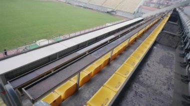 Amateur football stadium with grass field and gates. Empty fan tribunes before start of match. Observation and CCTV technology. Monitoring system. Concept of social safety. Security camera shooting.