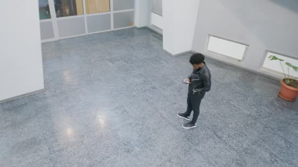 People Walking College Lobby African American Man Stands Texts Phone — Vídeo de stock