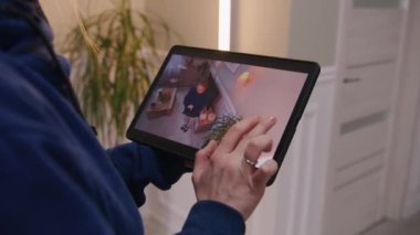 Beyaz kadın kurulumdan sonra güvenlik kameralarını kontrol ediyor. Kadın evdeki kamera açısını ayarlıyor ve dijital tablet ve uygulamayla döndürüyor. İzleme sistemi, güvenlik ve gizlilik kavramı.