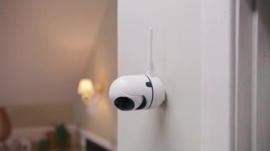 Close up shot of installed security camera on wall in modern apartment. CCTV camera with microphone and motion sensor. Concept of tracking system, surveillance and personal privacy. Dolly zoom.