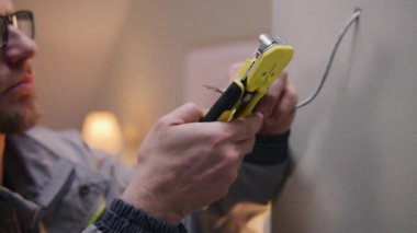 Üniformalı ve gözlüklü tamircinin yakın çekimi kablolu TV ile çalışıyor. Elektrikçi dairedeki profesyonel aletle izolasyonu kaldırıyor. İnternet Kurulumu.
