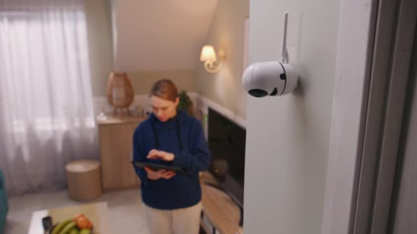 白人女人安装了监控摄像头妇女在家里设置闭路电视摄像头的角度 并与数字平板电脑和应用程序进行旋转 监测系统的概念 安全和隐私 — 图库视频影像