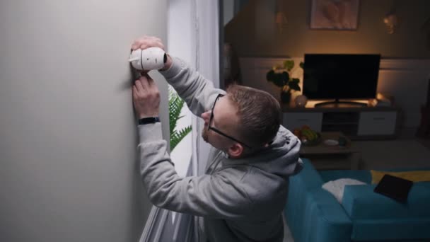 Man Puts Security Camera Wall Mount Living Room Connects Cable — Stockvideo