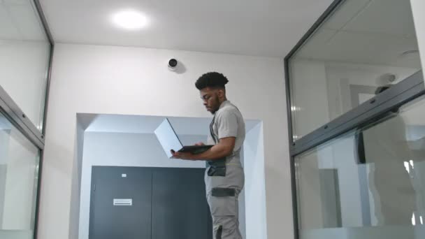 Muž Instalátor Uniformě Nastaví Bezpečnostní Kameru Chodbě Kanceláře Pomocí Notebooku — Stock video
