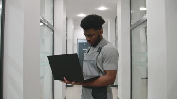 Üniformalı Afro Amerikalı Kurucu Koridorda Duruyor Dizüstü Bilgisayardaki Yazılımı Kullanarak — Stok video