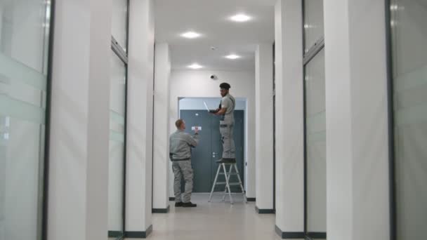 Two Multi Ethnic Installers Uniform Sets Security Camera Office Hallway — 图库视频影像