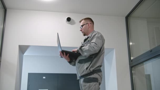 Установщик Униформе Устанавливает Камеру Безопасности Офисной Комнате Помощью Ноутбука Человек — стоковое видео