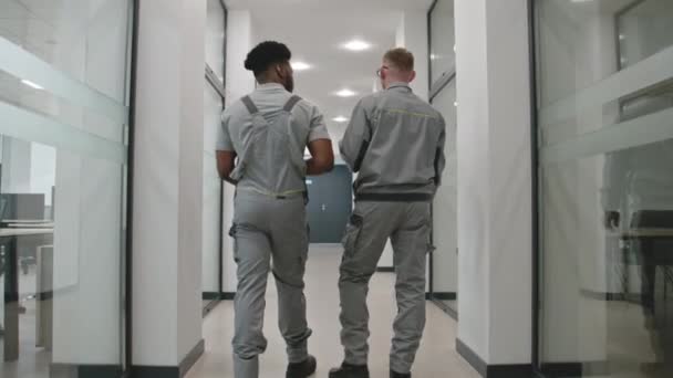 Back View Two Diverse Men Uniform Walk Hallway Discuss Cctv — Stockvideo