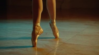Cinematic close up shot of classical ballet dancer feet in pointe shoes. Female dancer on choreography rehearsal in opera. Professional ballerina trains moves before start a show. Graceful ballet art.