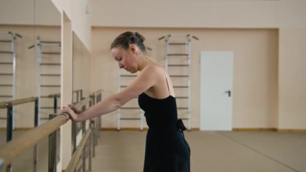 Female Ballet Dancer Training Bodysuit Stands Ballet Barre Doing Gymnastic — Stockvideo