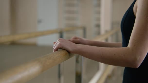 ダンススタジオのバレエ バレエの近くにあるトレーニング ボディスーツのバレリーナは 足を伸ばし パフォーマンスの準備をしています 女性バレエダンサーは体操を行う 古典バレエ舞踊学校 — ストック動画