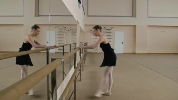 Изящная Балерина Тренировочном Кузове Стоит Рядом Балетным Баром Растягивает Ноги — стоковое видео