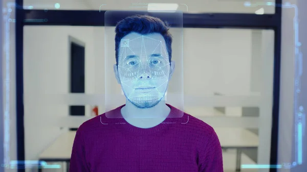Man scans face in office. He touches sensor and security system identifies person for access. 3D hologram of human innovative biometric facial recognition. Privacy, identification and AI technology.