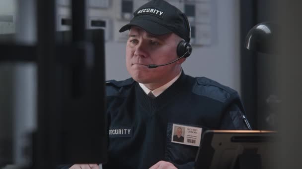 Poważny Oficer Ochrony Słuchawkach Siedzi Miejscu Pracy Wygląda Widok Kamery — Wideo stockowe