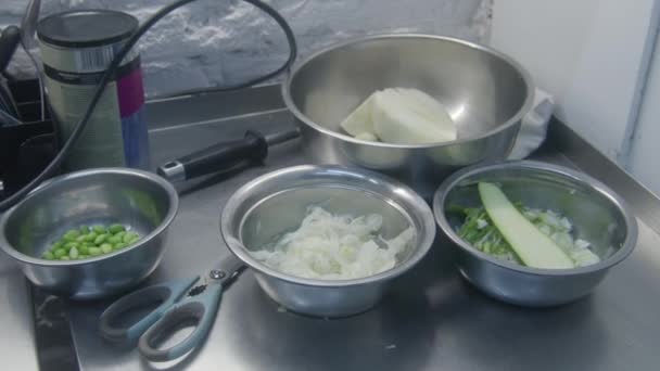为以后的菜准备了配料 厨房器皿旁边的桌子上放着装有切碎和切片蔬菜的金属碗 烹调的过程 有专业烹调的餐厅 公共饮食 — 图库视频影像