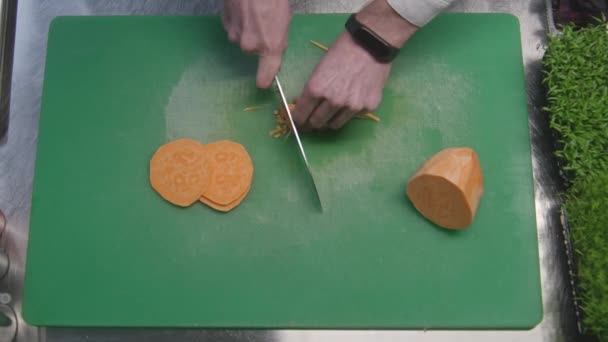 人在切板上把红薯切成小块 专业厨师的手部特写 厨房桌上的蔬菜和蔬菜 烹调美味佳肴的过程 公共饮食 素食菜 — 图库视频影像