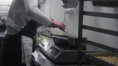 Şef fırında lezzetli yemekler pişirir. Erkek aşçı mutfakta çalışır, soslu peyniri rendeler ya da tencerede çorbayı. Yemek pişirme süreci. Profesyonel gurme mutfağı olan bir restoran. Kamu hizmeti.