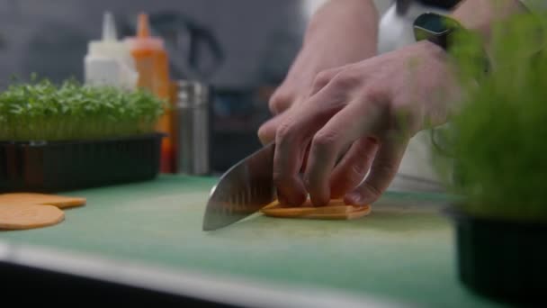 厨师在切菜板上切红薯 专业厨师的手部特写 厨房桌子上的绿色和其他配料 烹调美味佳肴的过程 公共饮食 素食菜 — 图库视频影像