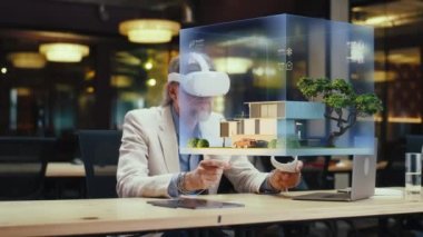 Erkek tasarımcı VR kulaklık ve kablosuz kontrolör kullanır, mimari proje yapar, sanal gerçeklikte ev dış tasarımı yaratır. Modern yüksek teknoloji şirketi. Üç boyutlu hologram. Gelecekteki dijital teknolojiler.