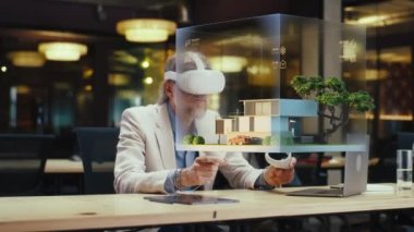 Erkek tasarımcı VR kulaklık ve kablosuz kontrolör kullanır, mimari proje yapar, sanal gerçeklikte ev dış tasarımı yaratır. Modern yüksek teknoloji şirketi. Üç boyutlu hologram. Gelecekteki dijital teknolojiler.