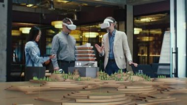Erkek mimar sanal gerçeklikteki modern yüksek teknoloji binasını ve park mimari projesini meslektaşlarına sunar. Üç boyutlu hologram. Gelecekteki dijital yapay zeka teknolojileri.