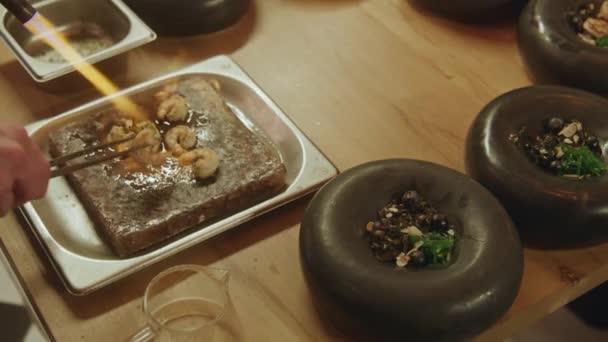 在现代的小酒馆里 厨师把虾仁和火锅式的大菜一起烹调 厨师用煤气炉把它点着 放在盘子里 膳食制作 公共饮食业及专业烹调概念 — 图库视频影像