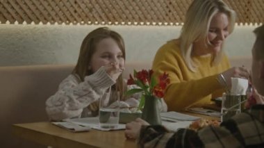 İki çocuklu anne aile yemeği yiyor, konuşuyor ve modern gastro kafede lezzetli yemekler yiyor. Mutlu aile doğum gününü kutlar, boş zamanlarını ya da hafta sonunu birlikte restoranda geçirirler. Kamu hizmeti konsepti