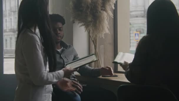 Официантка Приносит Людям Меню Афроамериканец Сидит Столом Кафе Разговаривает Женщиной — стоковое видео