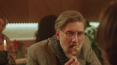Yetişkin bir adamın lezzetli yemekler yerken ve modern gastro kafede arkadaşlarıyla konuşurken yakın çekim. Doğum gününü kutlar, aile yemeği yer, hafta sonunu restoranda geçirir. Toplu yemek kavramı.