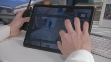 Güvenlik görevlisinin dijital tablet bilgisayardaki güvenlik kameralarını yakından çek. Modern yazılım güvenlik kameralarını ekranda gösteriyor. Yüksek teknoloji güvenlik. Sosyal güvenlik kavramı.