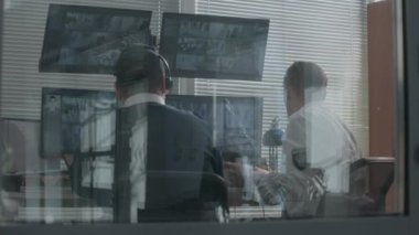 Güvenlik görevlileri güvenlik kameralarını bilgisayarda görüntüler ve sabit telefon kullanırlar. Güvenlik kameralarının tarama sistemli görüntülerini gösteren birden fazla ekran. Gözlem teknolojisi. Sosyal güvenlik kavramı.