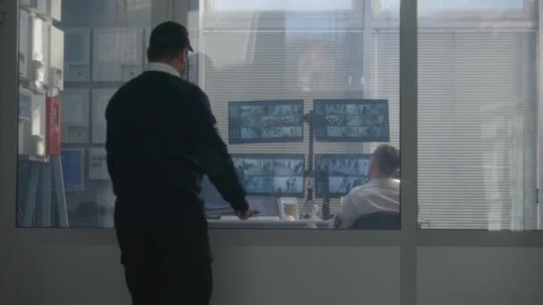 警備員は同僚の部屋に入る 防犯カメラ監視カメラ 監視カメラの映像を示す画面とトランシーバーやコンピュータを使用しています ハイテクセキュリティの概念 — ストック動画