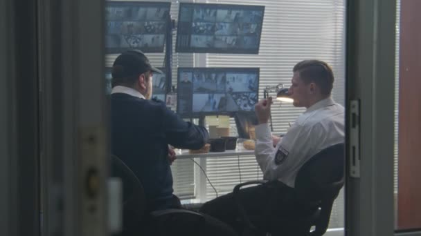 Två Vakter Pratar Äter Lunch Medan Kontrollerar Övervakningskameror Datorer Programvara — Stockvideo