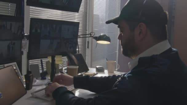 警備員は コンピュータ上のオフィスでCctvカメラを監視し 固定電話を使用します 画面上の顔認識と監視カメラの映像を示すハイテクプログラム 社会的安全の概念 — ストック動画